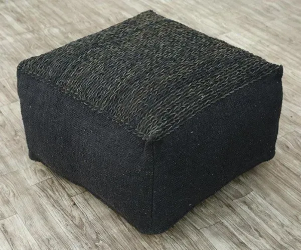 A black ottoman is sitting on a wooden floor