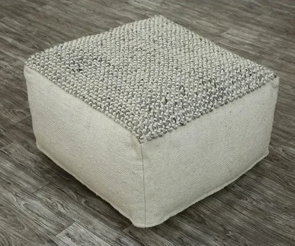 A white ottoman is sitting on a wooden floor.