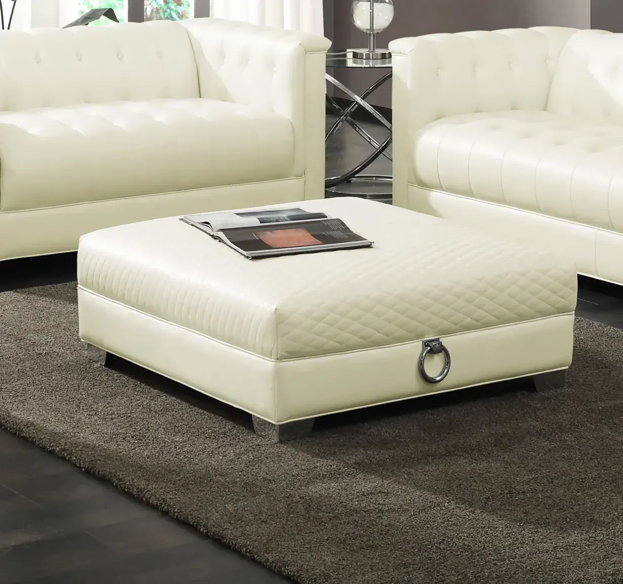 A white ottoman with a magazine on top of it in a living room