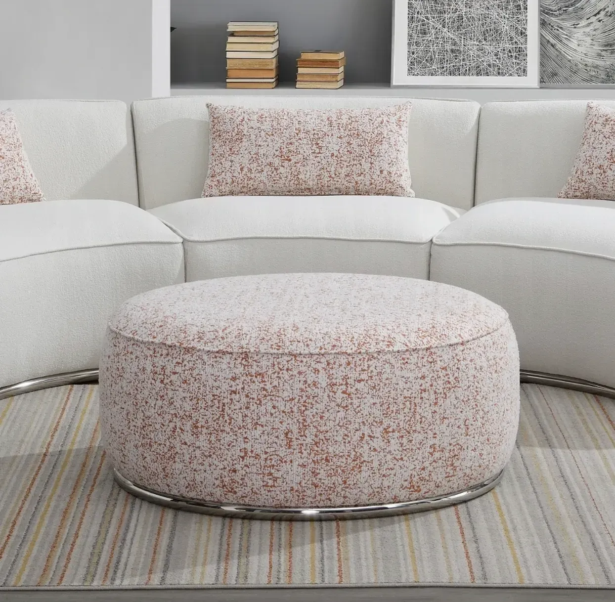 A round ottoman sits in front of a curved sectional couch