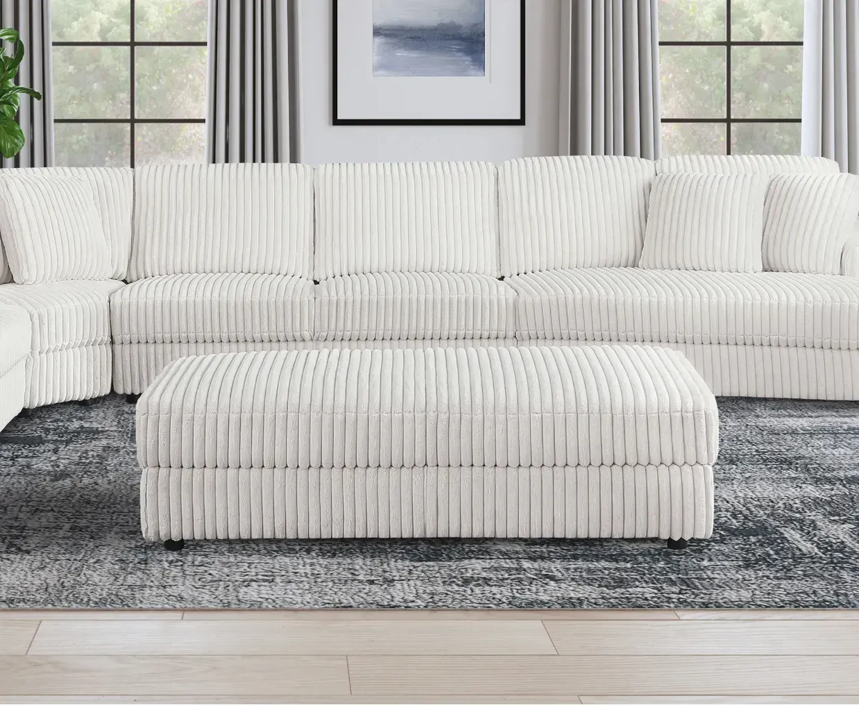 A living room with a sectional couch , ottoman , and rug.