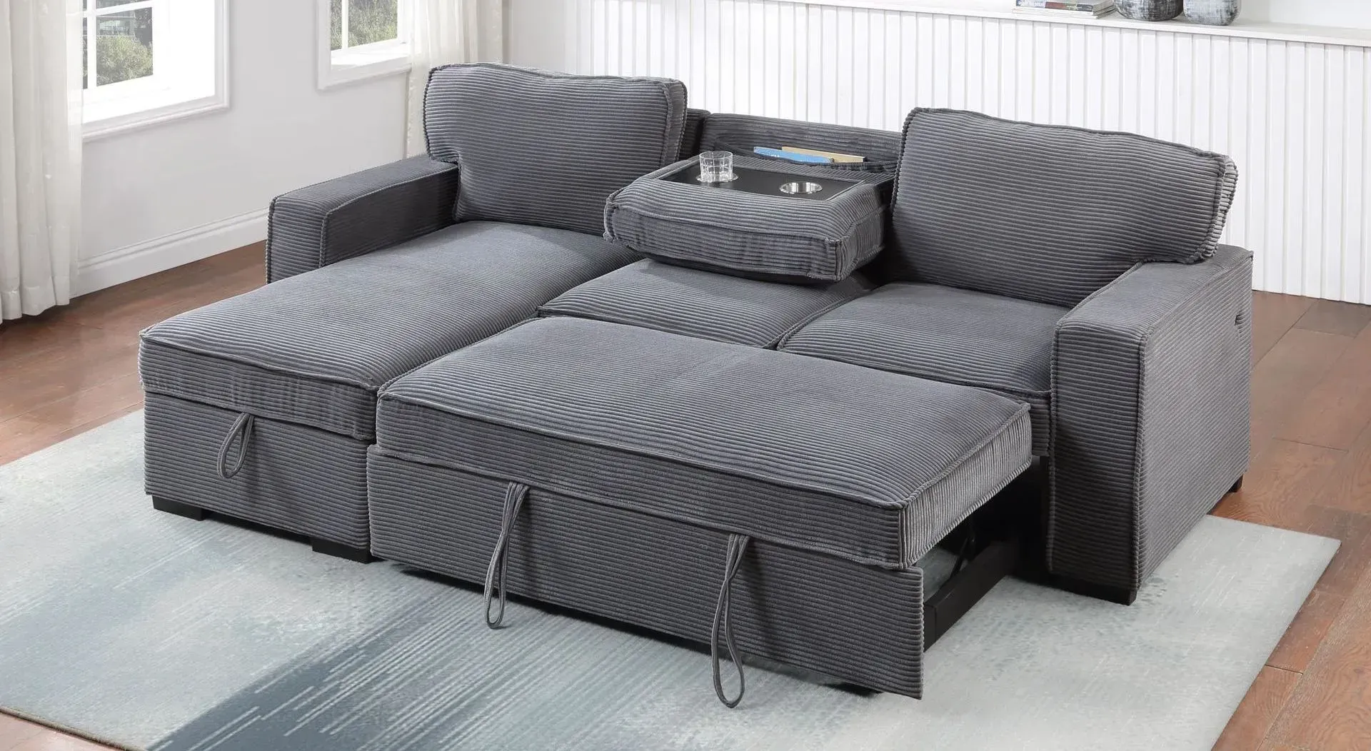 A grey couch is sitting on top of a white rug in a living room.