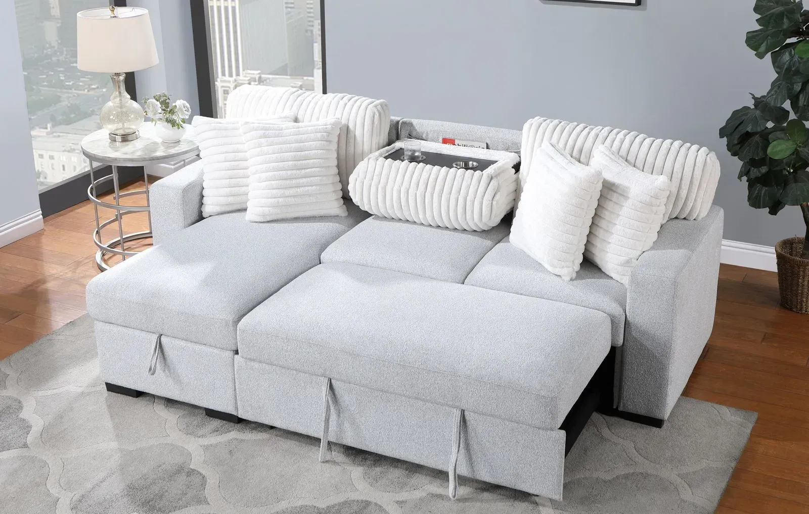 A grey sectional couch with pillows is sitting on a rug in a living room.