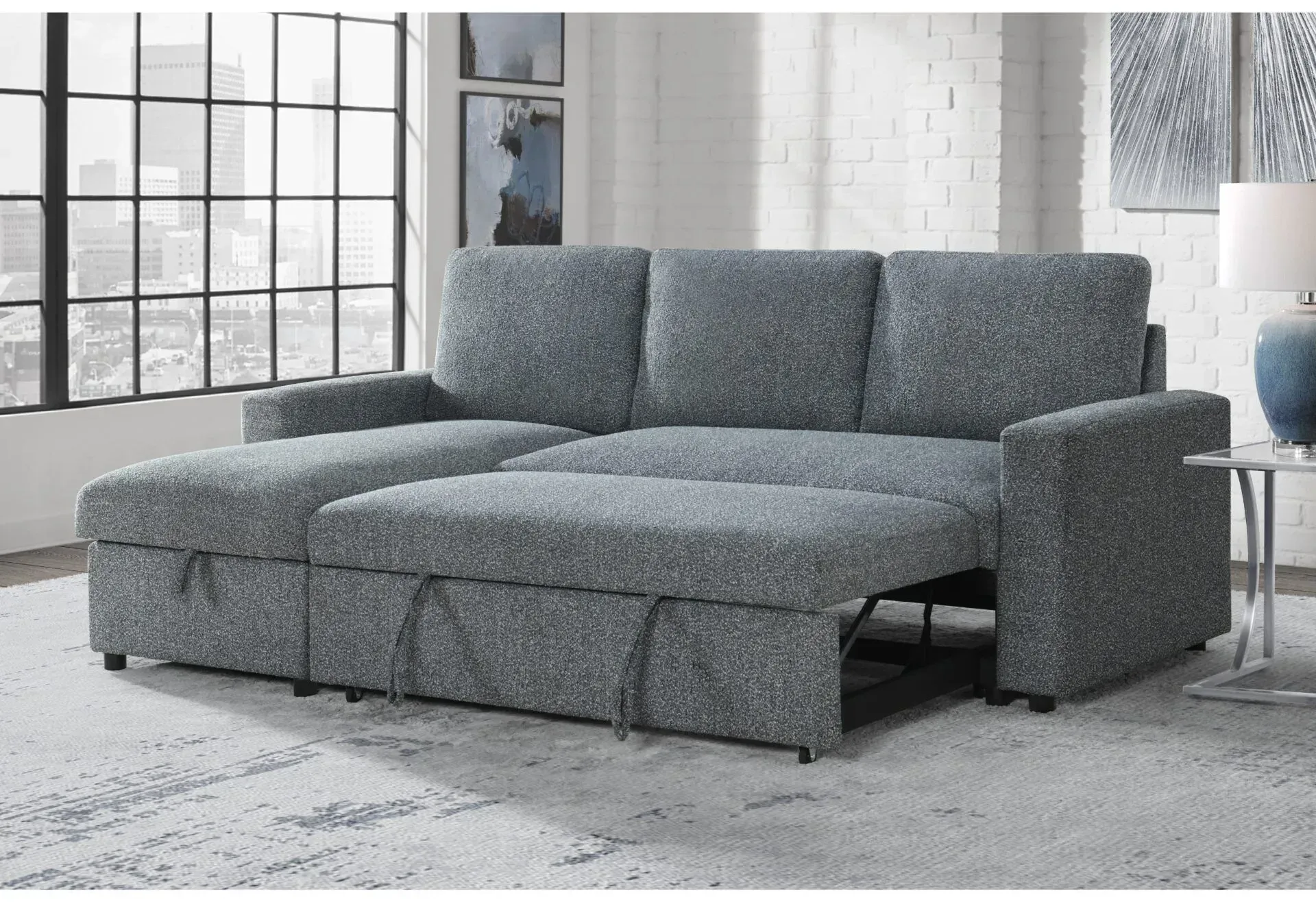 A grey sectional couch is sitting in a living room next to a window.