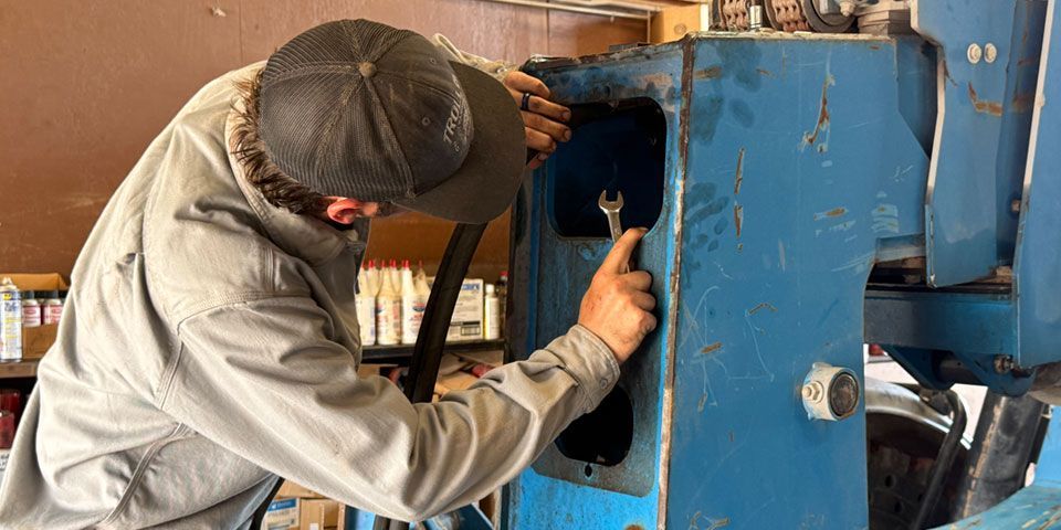 Mechanic performing maintenance on a construction vehicle in a repair shop