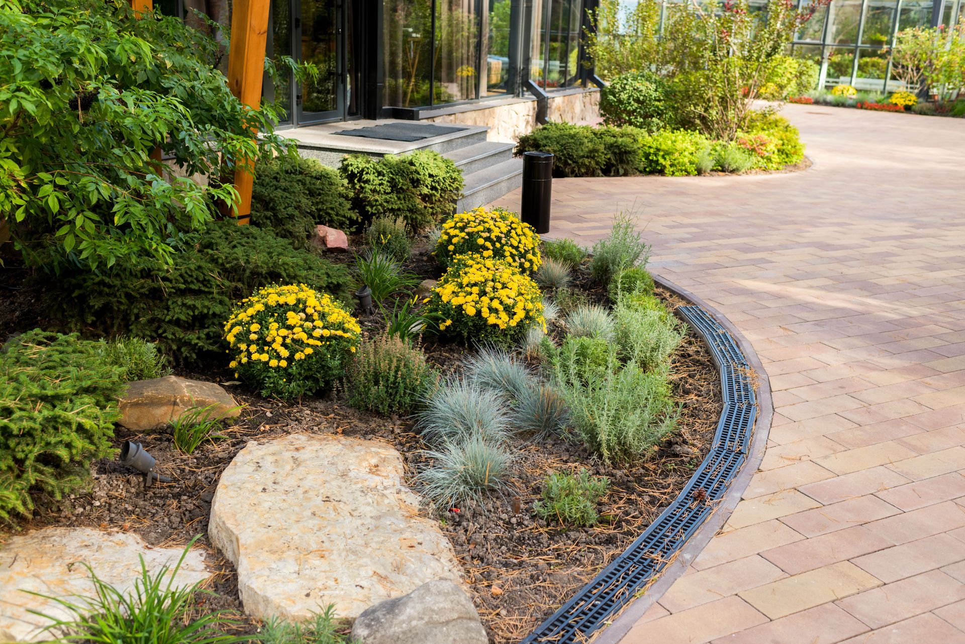 Curved garden path beside yellow flowers, greenery, and stone landscaping in a landscaped park