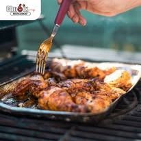 Hand grilling chicken on a grill; fork used for turning.