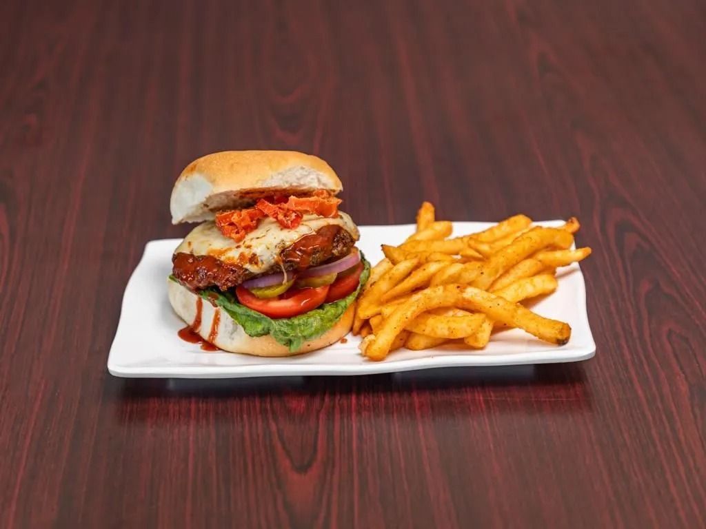 Burger with fries on a white plate on a wood table.