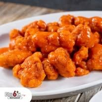 Buffalo chicken bites on a white plate, coated in orange sauce.