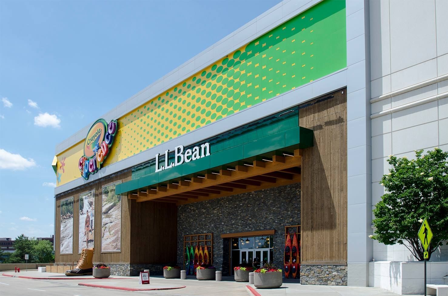 L.L.Bean store exterior with green awning, stone and wood facade, colorful sign, and blue sky.