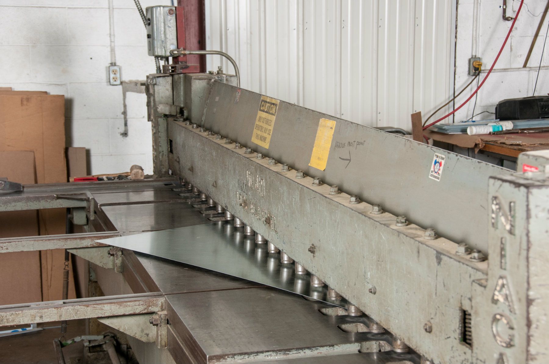 Metal shear machine in a workshop, cutting a sheet of metal.