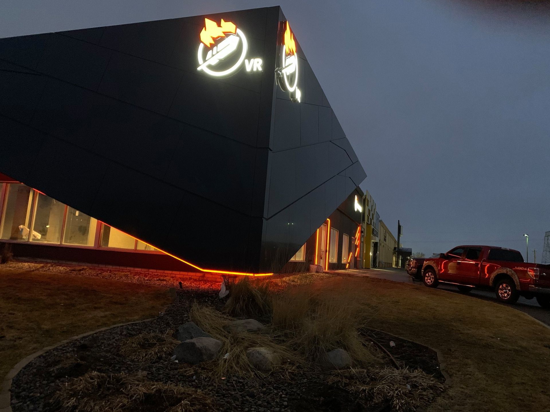 A modern, black building with illuminated logo 