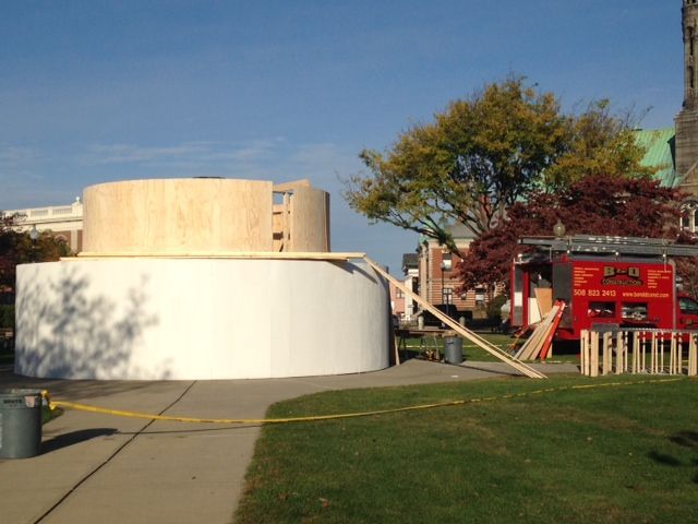 A large wooden structure is being built in a park.