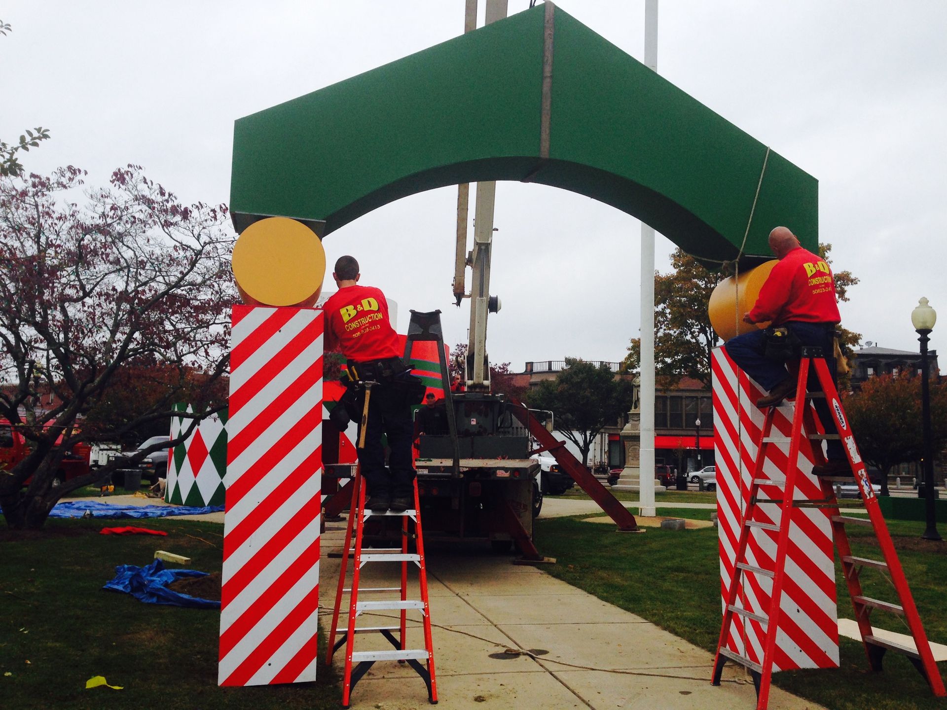 A group of men are working on a christmas decoration in a park.