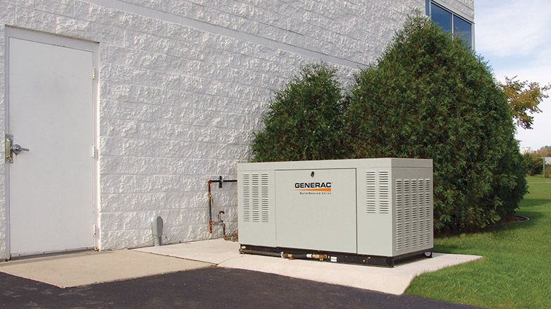 A generator is sitting outside of a building next to a door