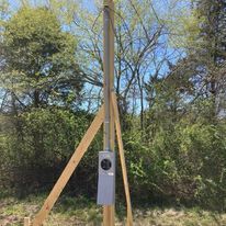 An electrical box is sitting on top of a wooden pole.
