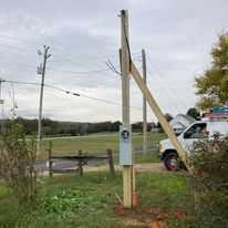 A white van is parked next to a wooden pole in a field.