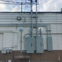 There are a lot of electrical boxes on the side of a building.