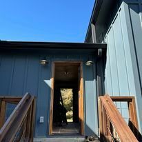 The front door of a house with a wooden ramp and stairs leading up to it.