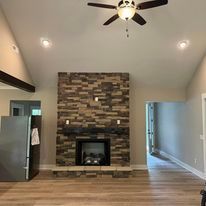 A living room with a fireplace and a ceiling fan.