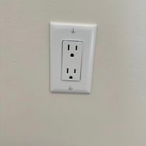 A white electrical outlet is mounted on a white wall.