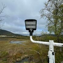 A street light is sitting on top of a pole in the middle of a field.