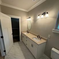 A bathroom with two sinks , a toilet and a mirror.