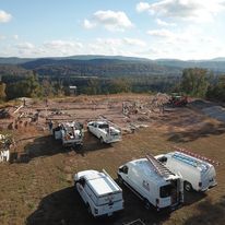 An aerial view of a construction site with trucks and vans parked in a field.
