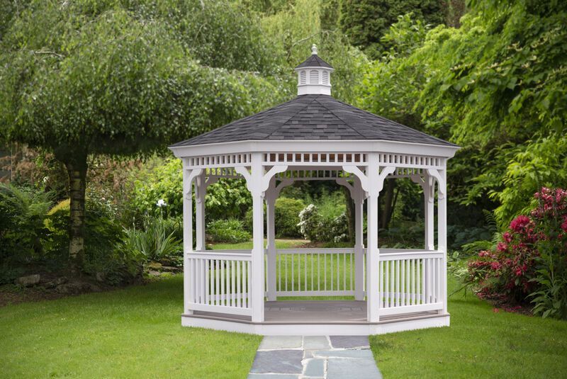 A white gazebo is sitting in the middle of a lush green garden.
