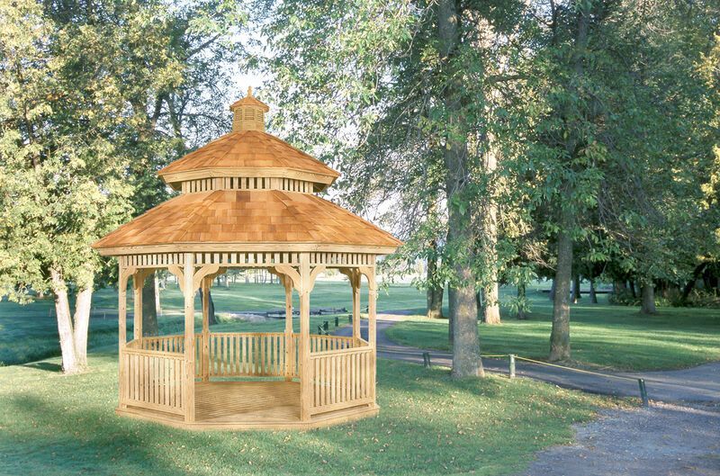 A wooden gazebo in a park surrounded by trees