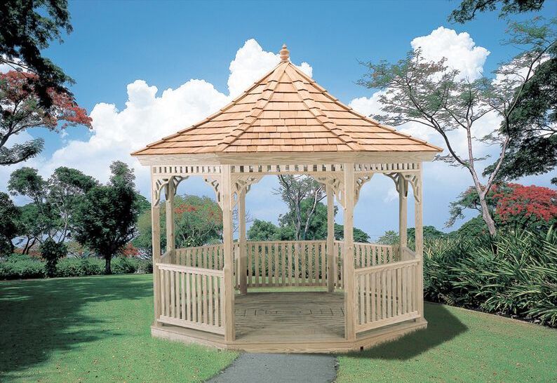 A wooden gazebo in a park with trees in the background