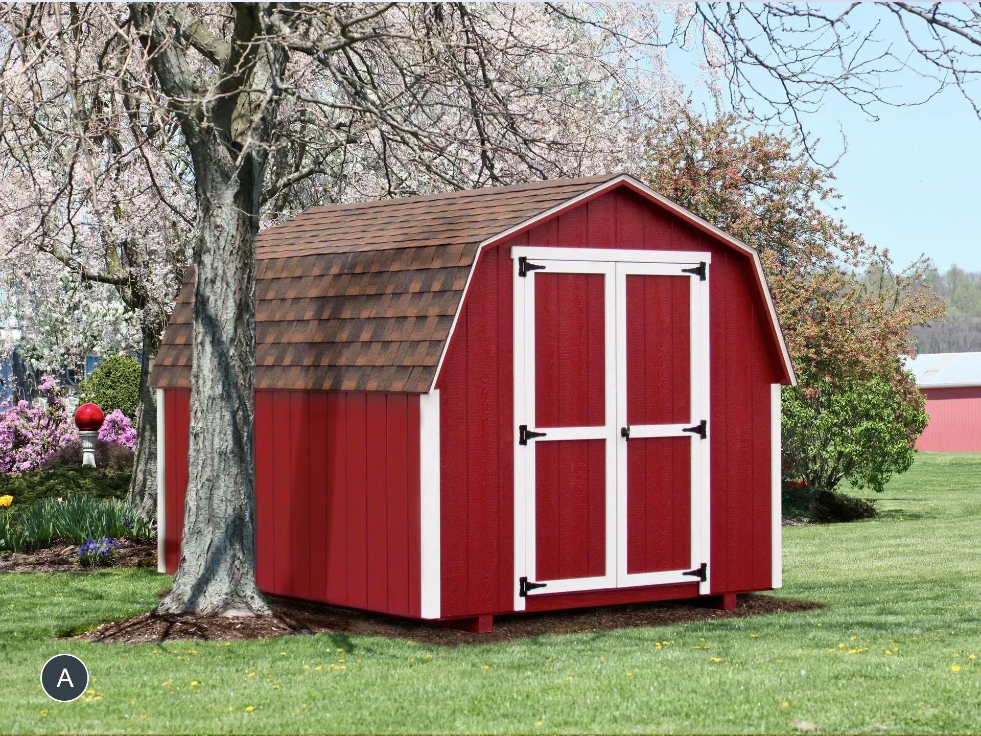 Red barn-style shed with white trim and brown roof in a grassy yard, near a tree.