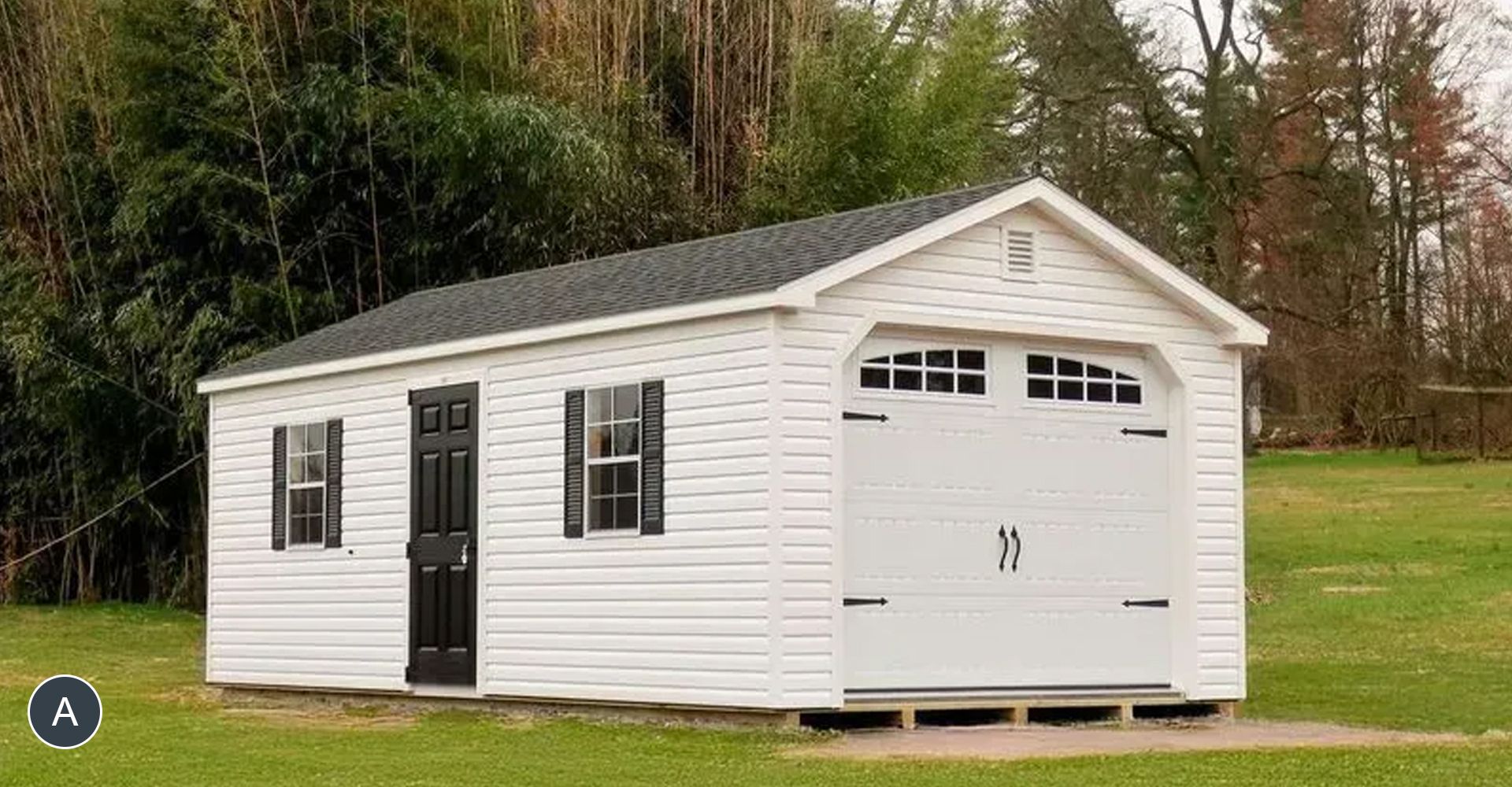 White shed with black door, shutters, and garage door, set on a grassy lawn.