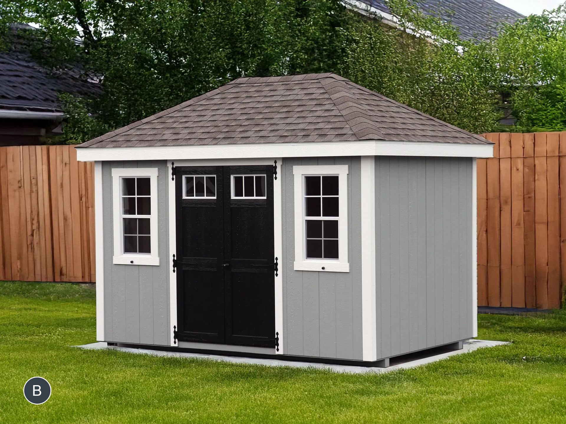 A gray shed with a black door and windows is sitting on top of a lush green lawn.