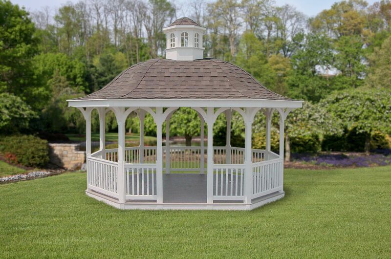 A white gazebo with a brown roof is sitting in the middle of a lush green field.