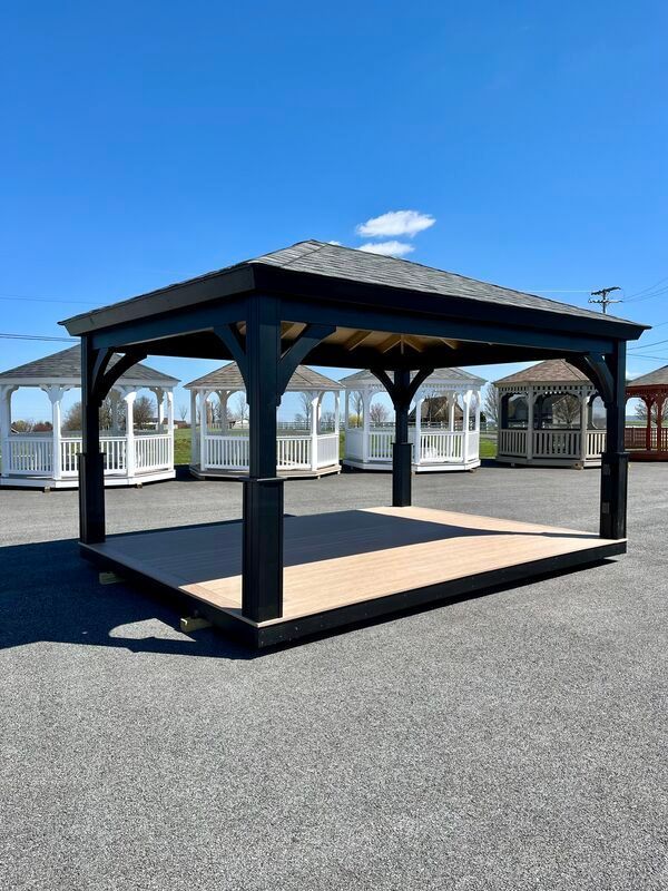 A black gazebo is sitting in the middle of a parking lot.