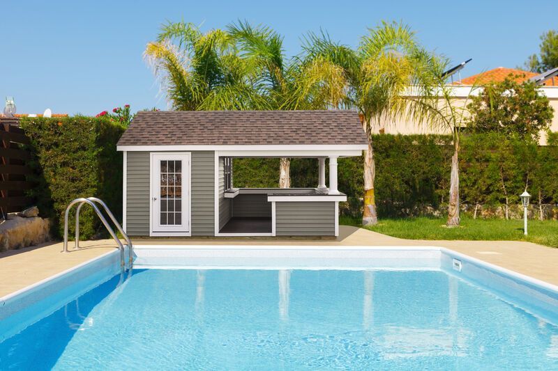 A shed is sitting next to a large swimming pool.
