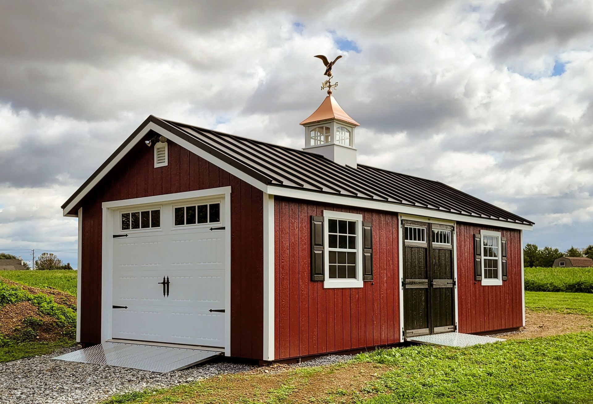 A red garage with a weather vane on top of it