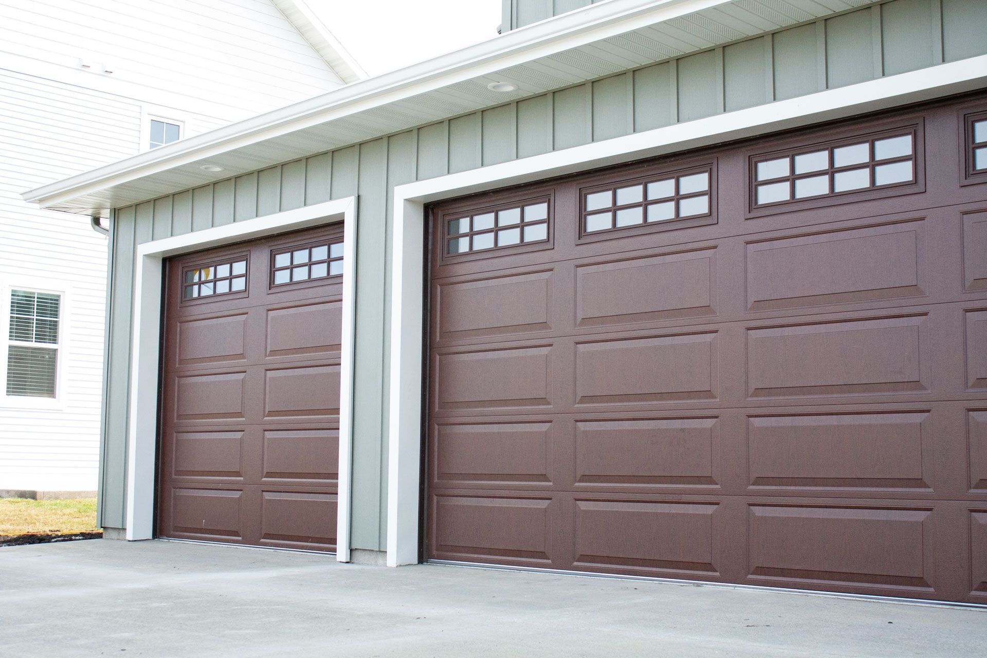 Three brown garage doors are sitting next to each other on the side of a house.