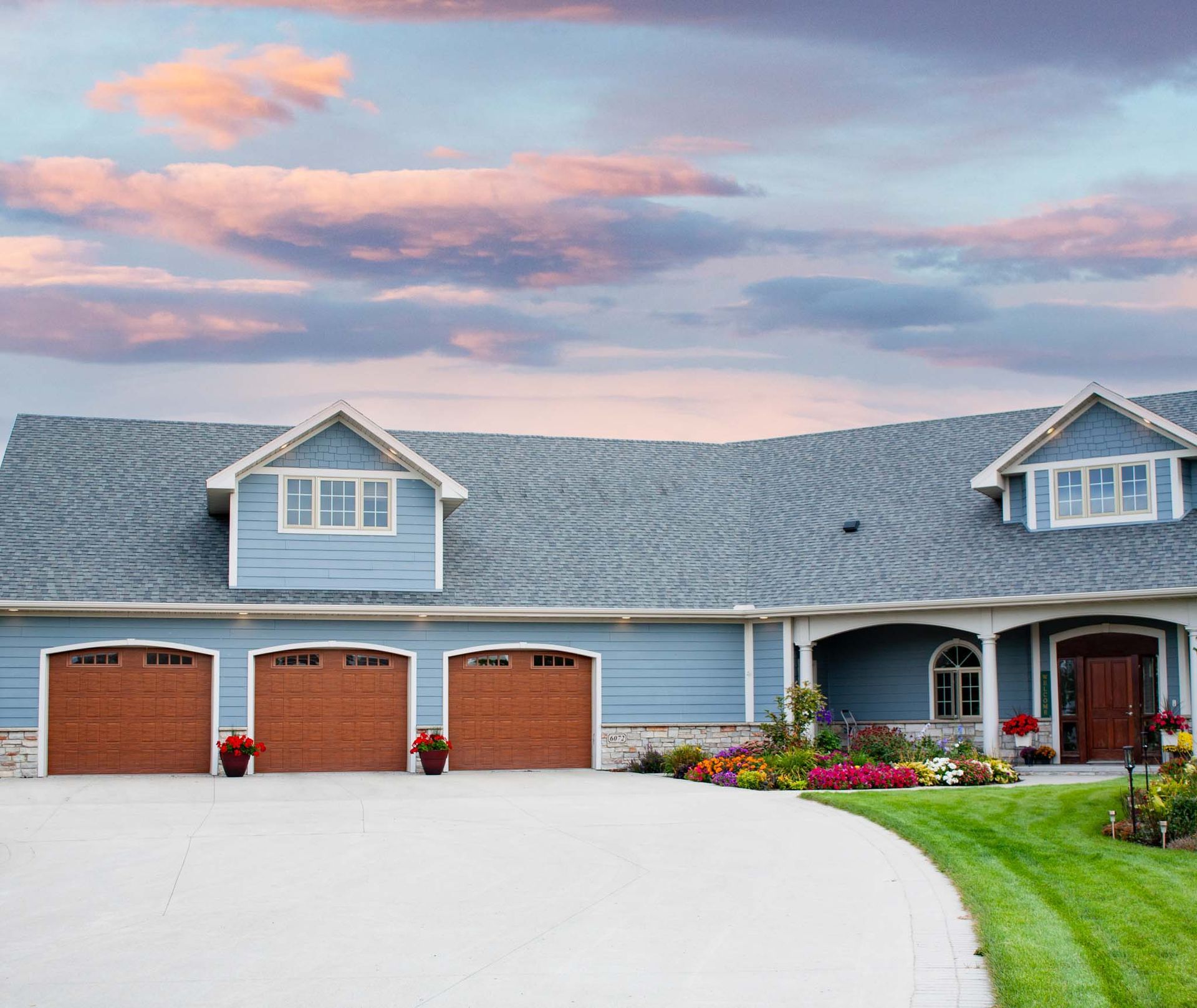 A large blue house with three garage doors and a driveway