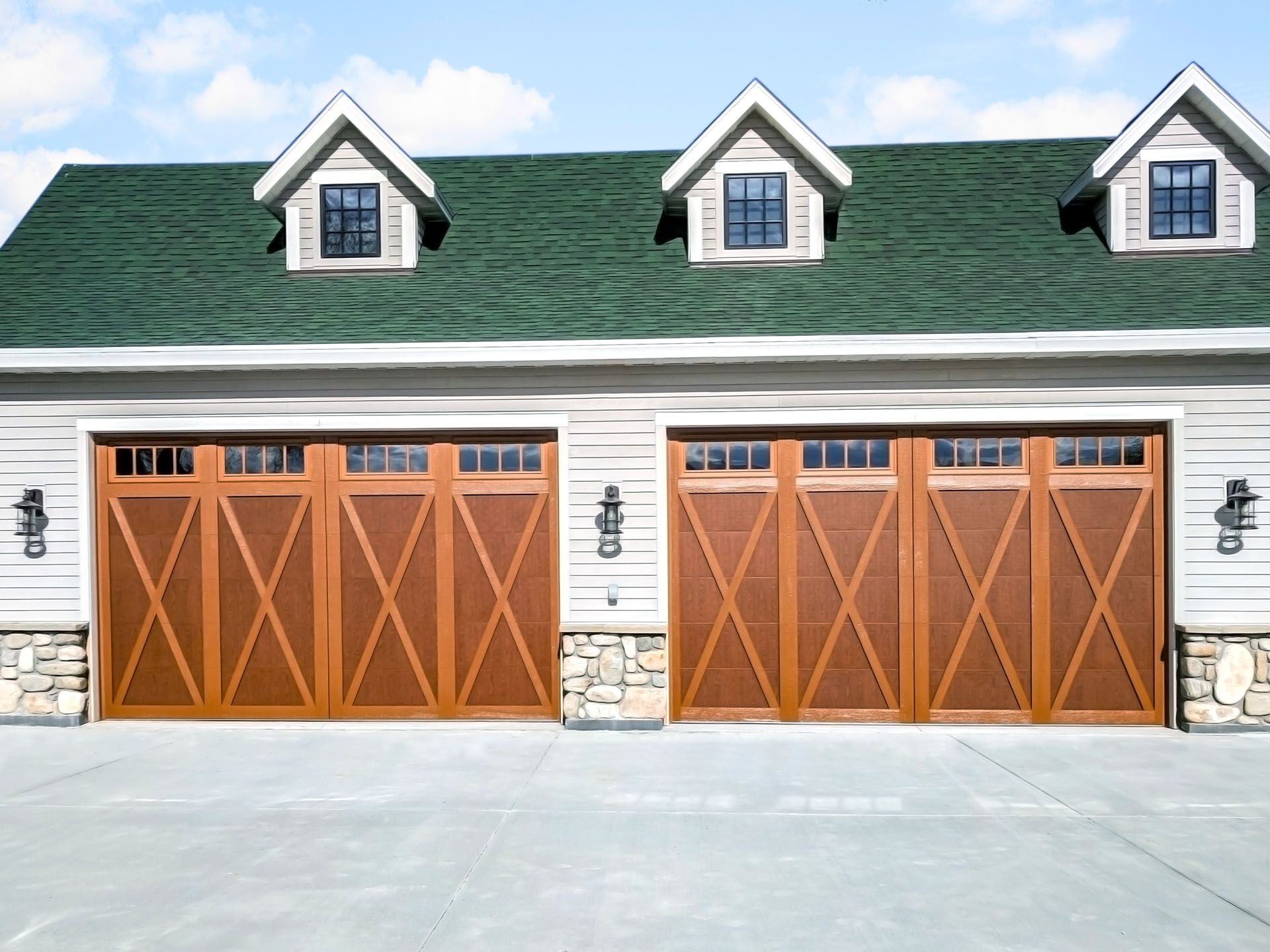 A garage with three wooden doors and a green roof