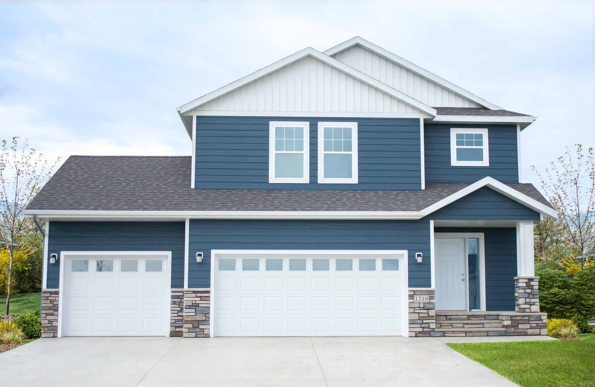 A large blue and white house with three garage doors.