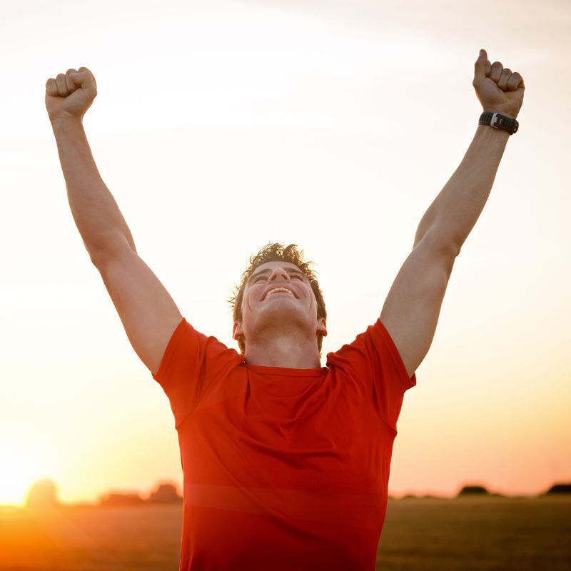 A man in a red shirt is raising his arms in the air