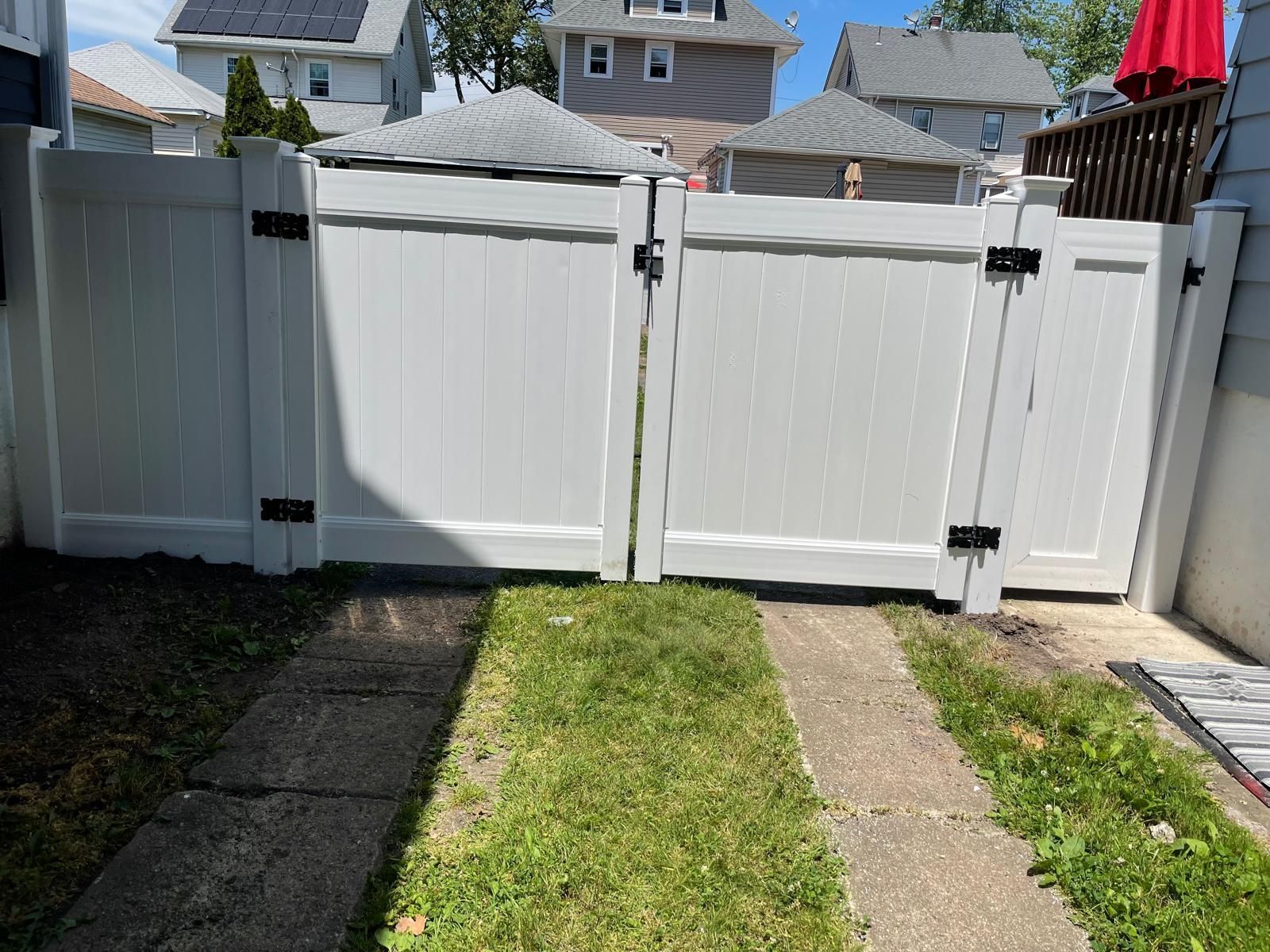 A white fence with a red umbrella in the background.