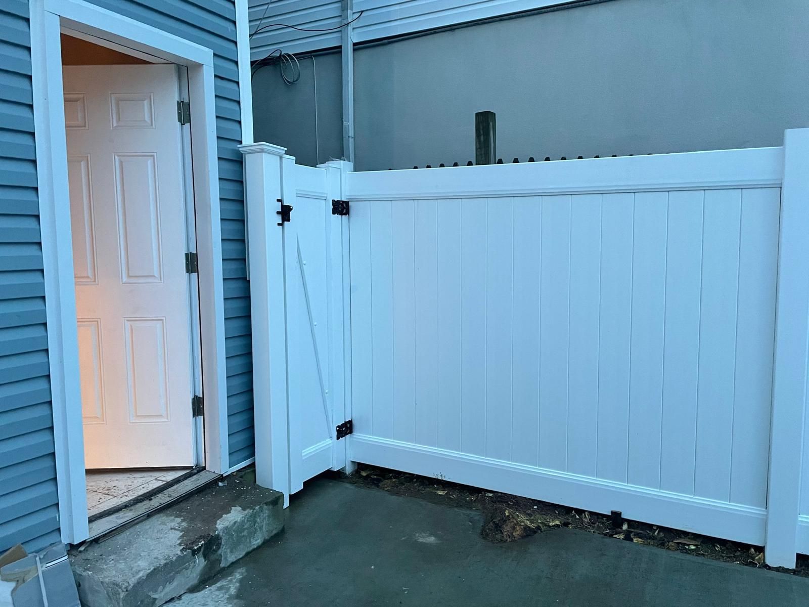 A white fence is sitting next to a blue house.