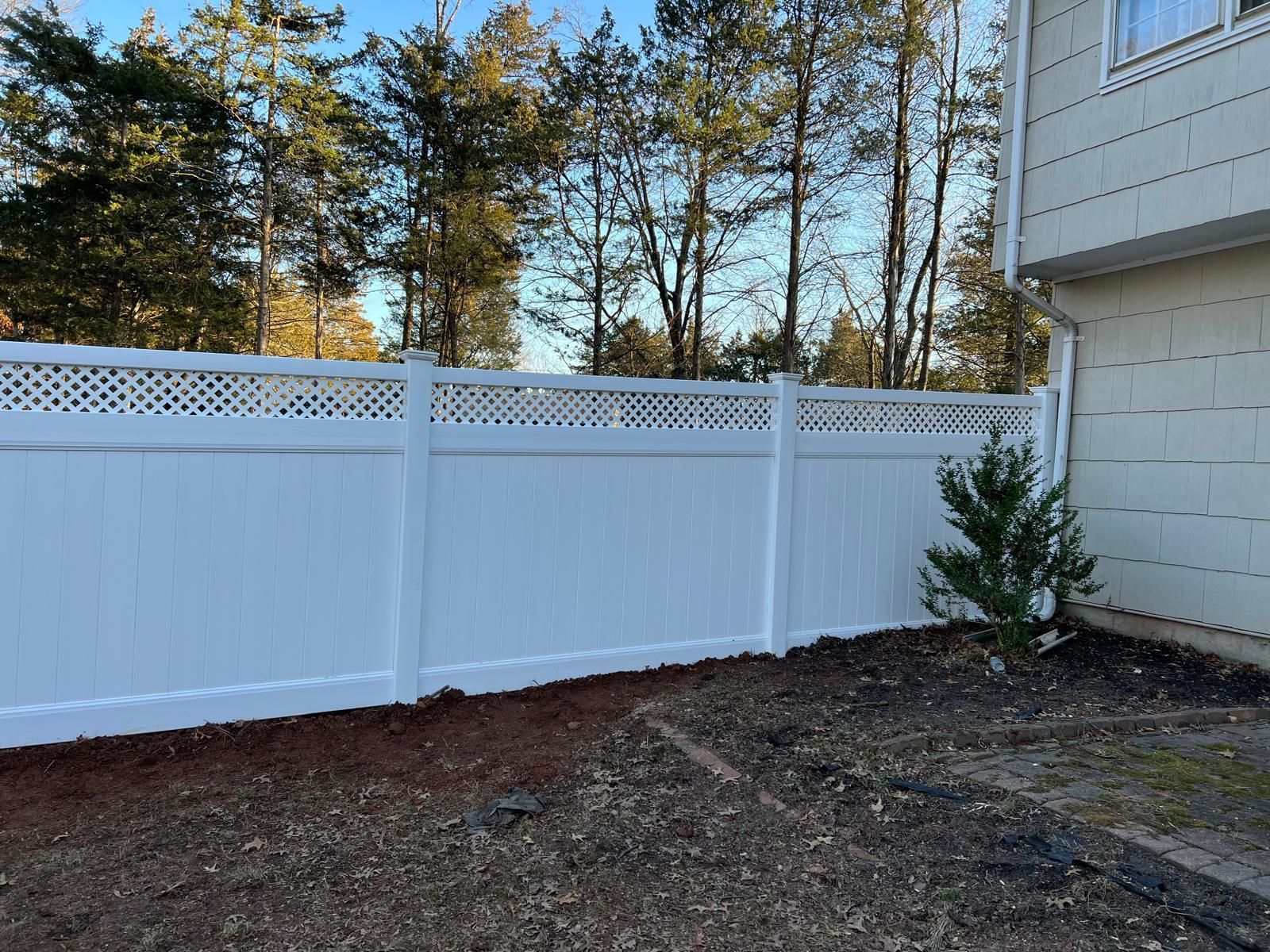 A white fence is in the backyard of a house.