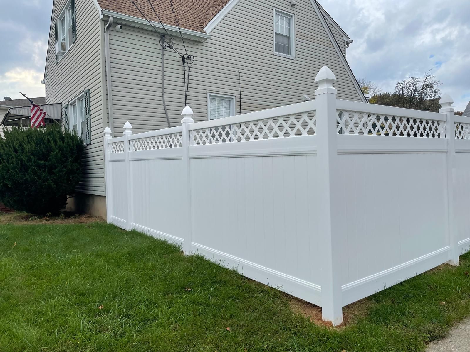 A white vinyl fence is in front of a house.