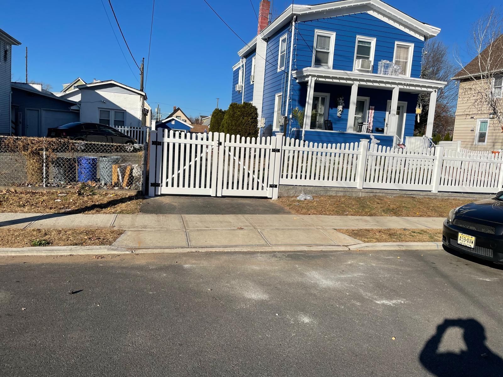A blue house with a white picket fence and a car parked in front of it.