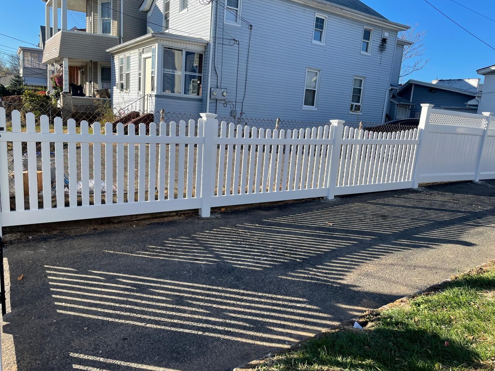A white picket fence is in front of a white house.
