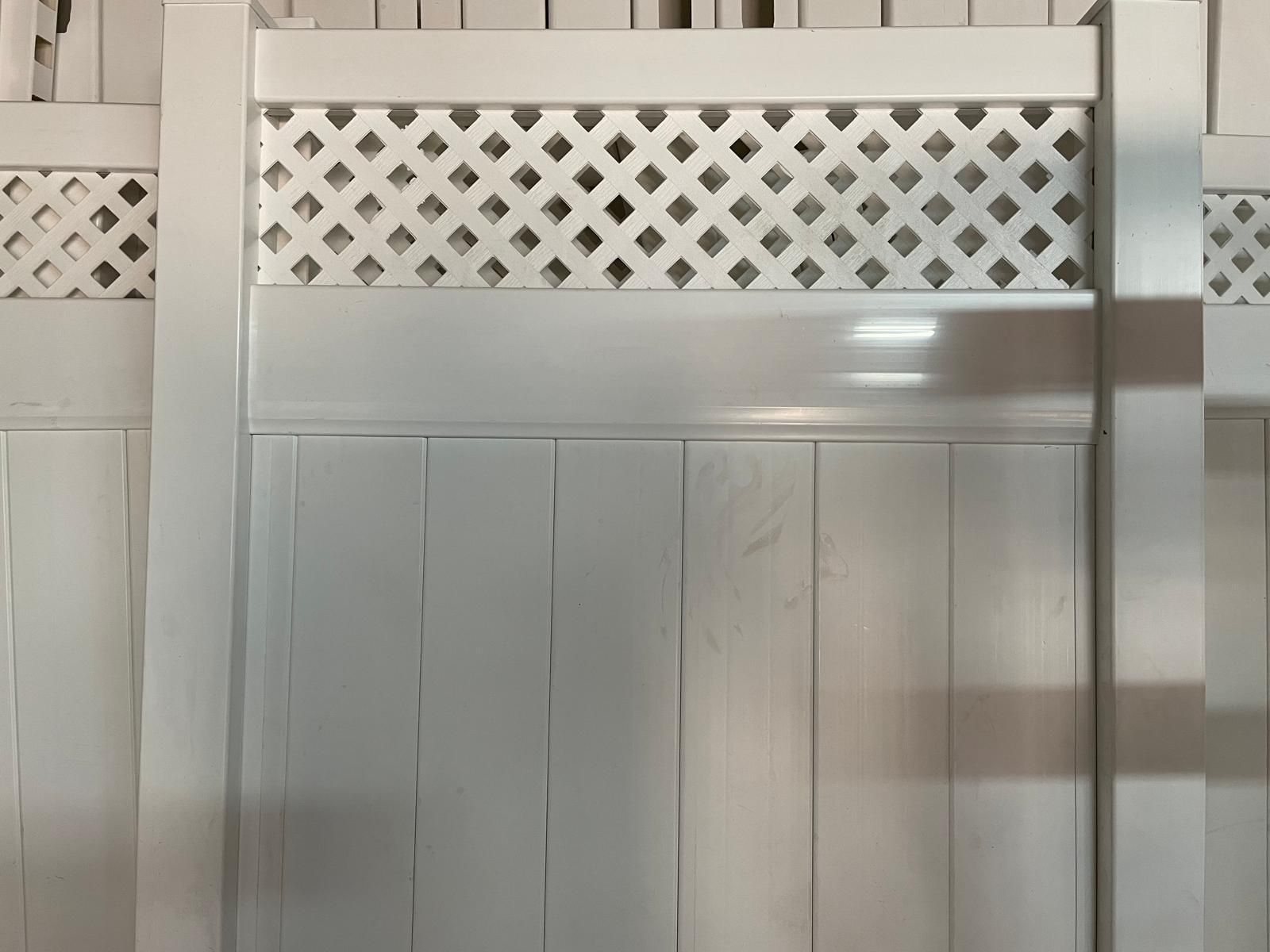 A close up of a white wooden fence with a lattice design.